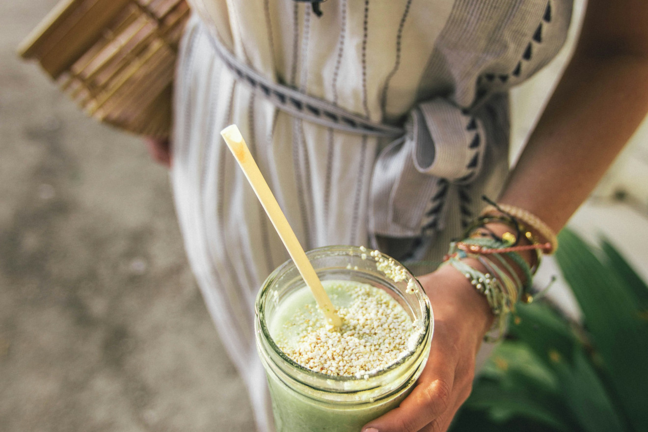 Mulher segurando um smoothie verde / Unsplash, Roberto Nickson