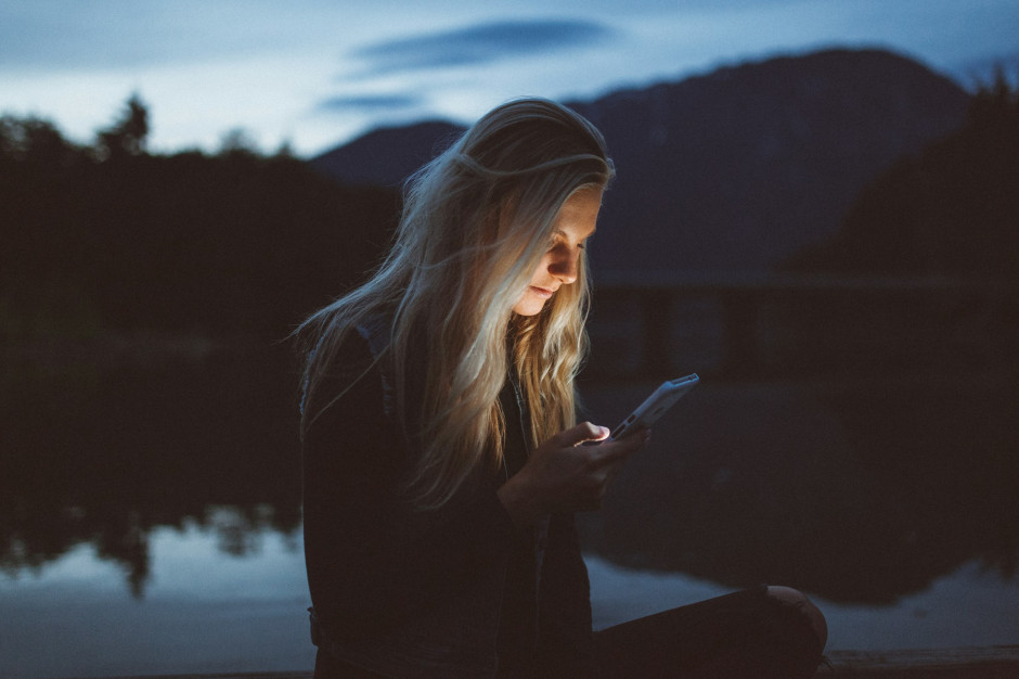 Jonge vrouw bladert 's avonds door haar telefoon - verslaving aan sociale media is een groeiend probleem in de moderne samenleving / Unsplash, Becca Tapert