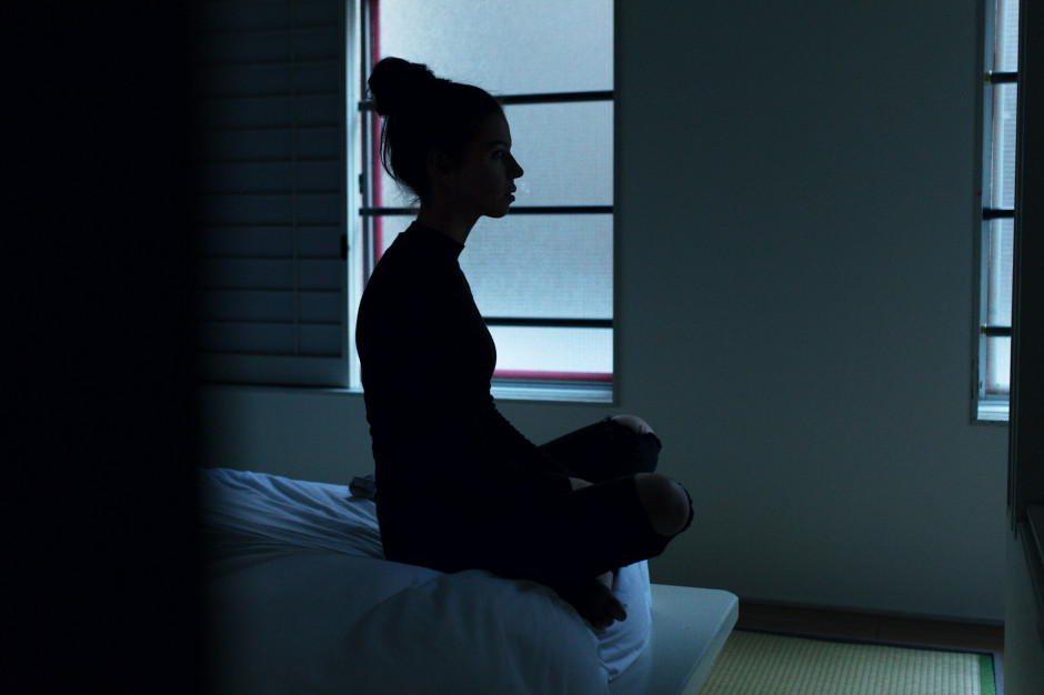 Donna che medita in una stanza buia / Unsplash, Ben Blennerhassett
