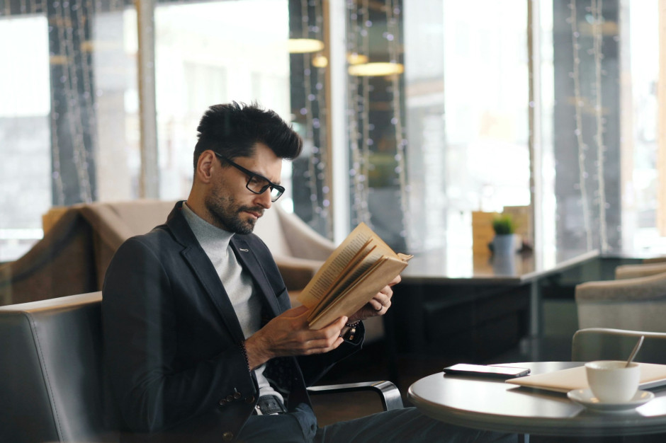 Homem de jaqueta lendo um livro / Unsplash, Vitaly Gariev